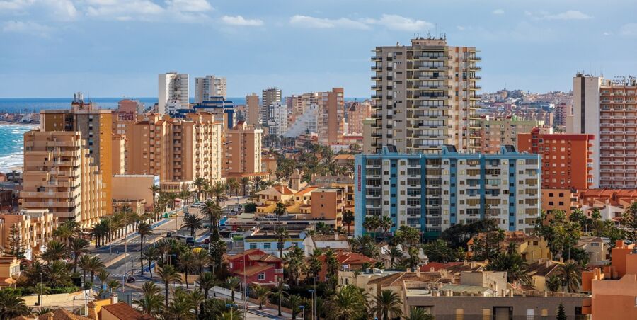 Vibrant coastal cityscape with diverse architecture, palm trees, and ocean backdrop.