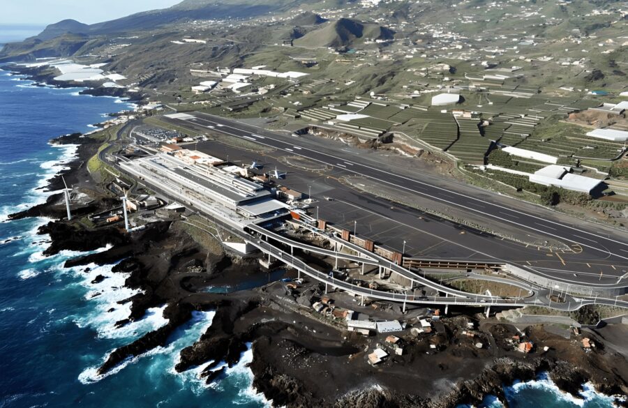 La Palma Airport runway on volcanic coastal cliff with terminal, apron, and Atlantic surf.