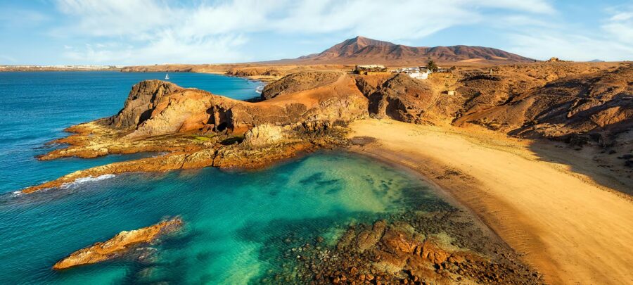 Papagayo Beach panoramic view with turquoise sea, golden sand, volcanic cliffs and remote coastline.