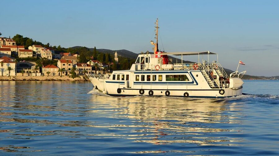 Ferry boat on tranquil waters near charming Mediterranean coastal town at sunset.