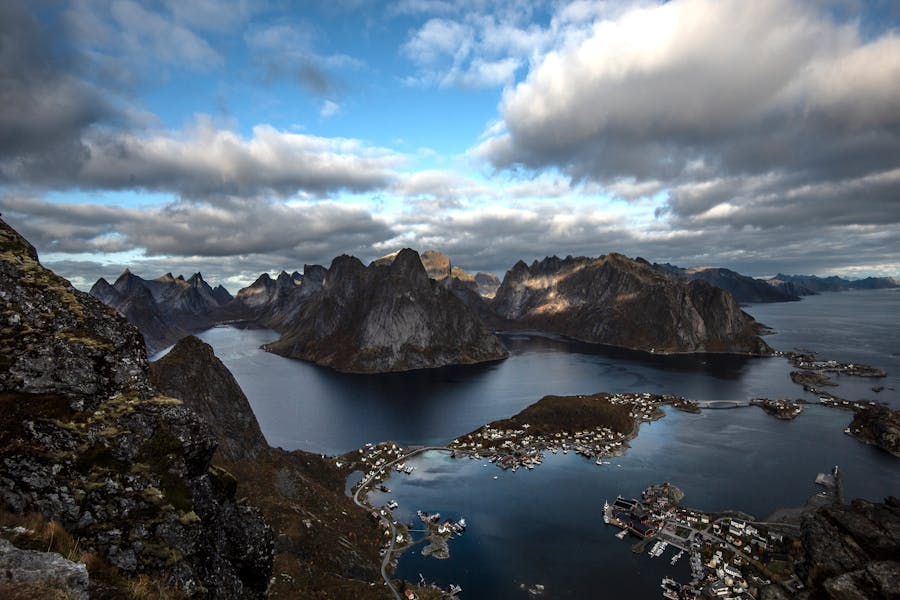 Reine, Lofoten: picturesque fishing village on fjord surrounded by dramatic mountains and sea.