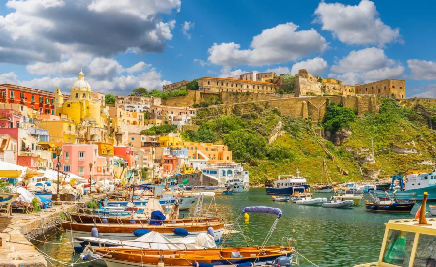 Marina Corricella coastal harbor with colorful boats and pastel seaside village.