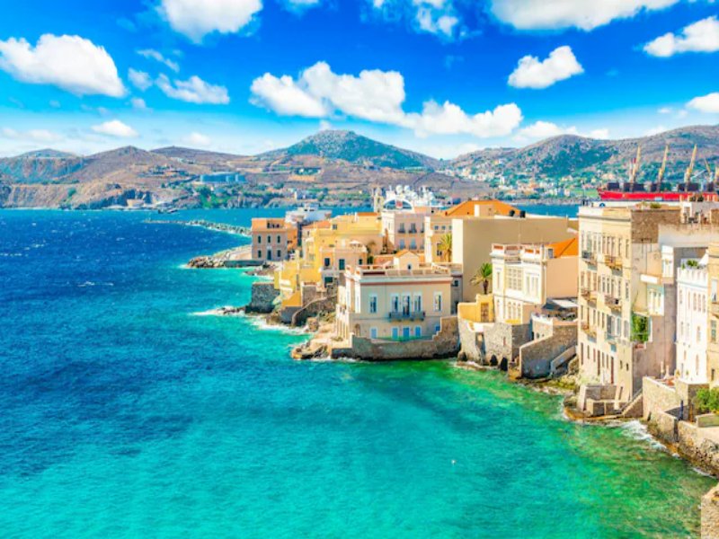 Syros, Greece waterfront harbor with Mediterranean houses and turquoise sea.