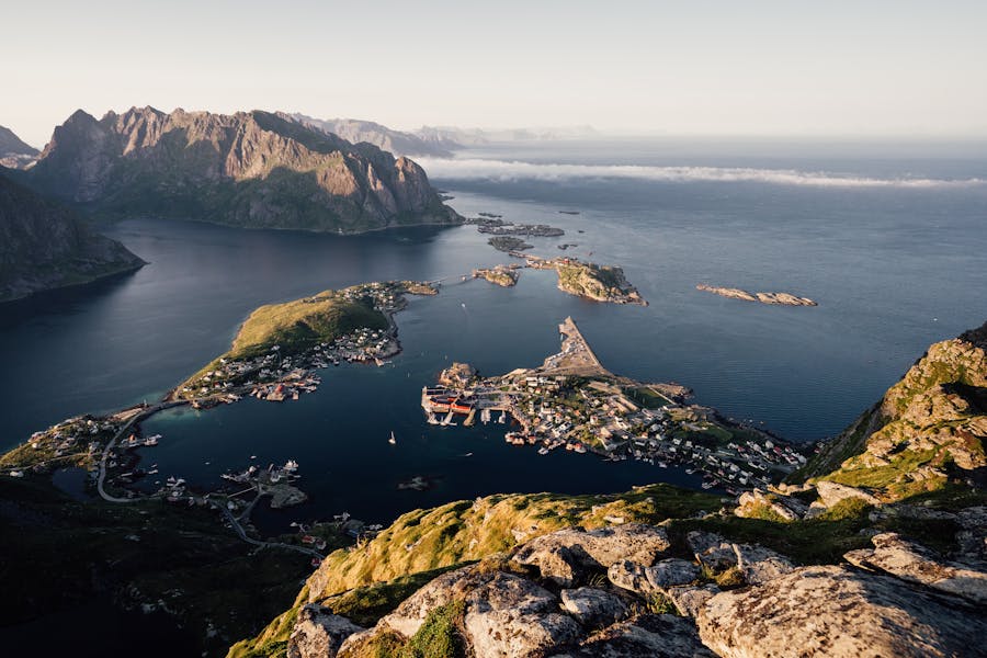 Lofoten Islands coastal harbor in Norway with fishing village, rugged mountains, and sea view.