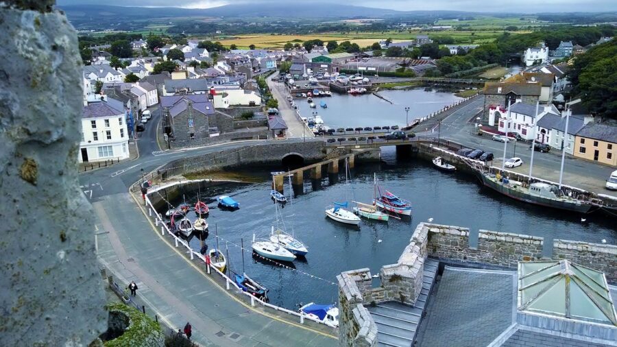 Scenic coastal harbor town view from old stone castle overlooking boats, bridge, and countryside.