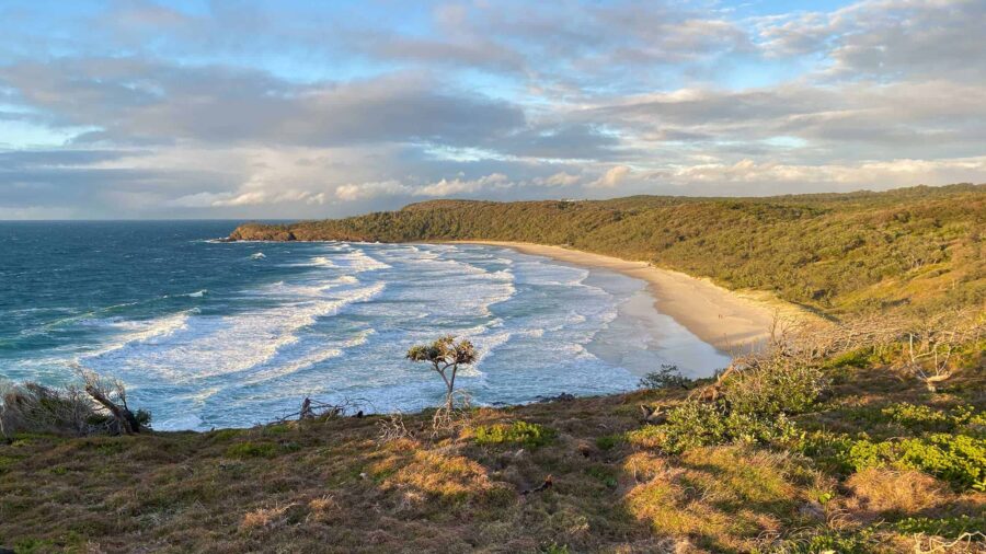 Scenic aerial view of Noosa National Park coastal headland, pristine sandy beach and blue ocean waves.