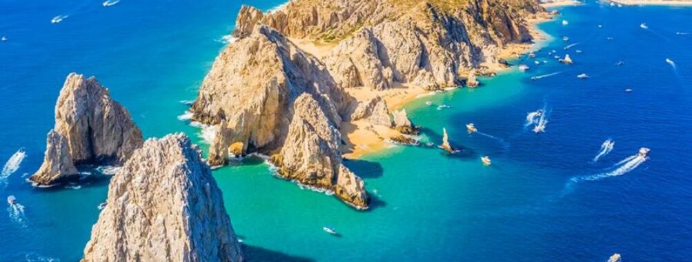 Aerial view of tropical coastline with azure ocean, rugged cliffs, and vibrant maritime activity.