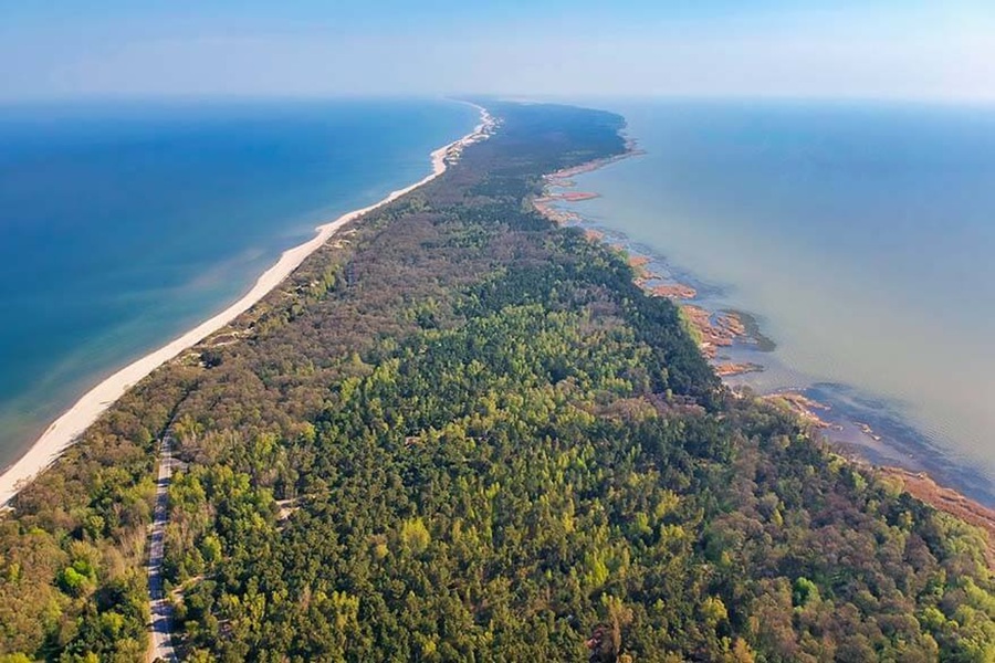 Aerial view of Curonian Spit coastline with beach, ocean, and forest.