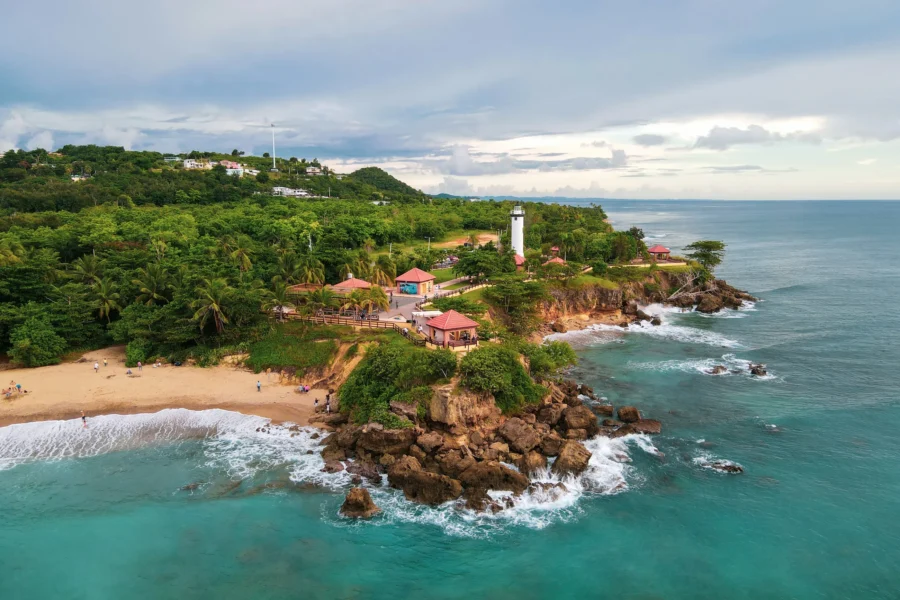 Aerial view of Rincón Puerto Rico coastline with rocky cliffs, sandy beach and lighthouse.