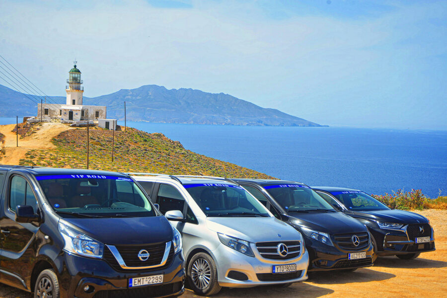 Coastal lighthouse with VIP cars, serene sea, blue sky, Mykonos private transfers.