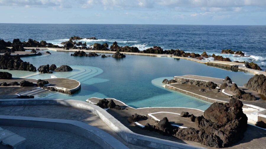 Natural volcanic rock pool by the Atlantic Ocean with serene blue water and dramatic scenery.