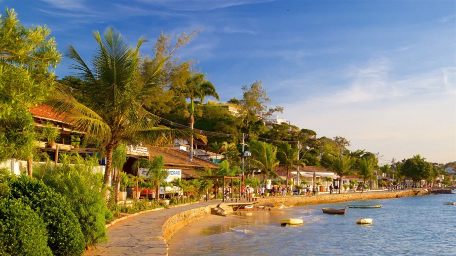 Scenic Brazilian coastal promenade at Alto do Humaitá with palm trees, boats, waterfront cafes at sunset.