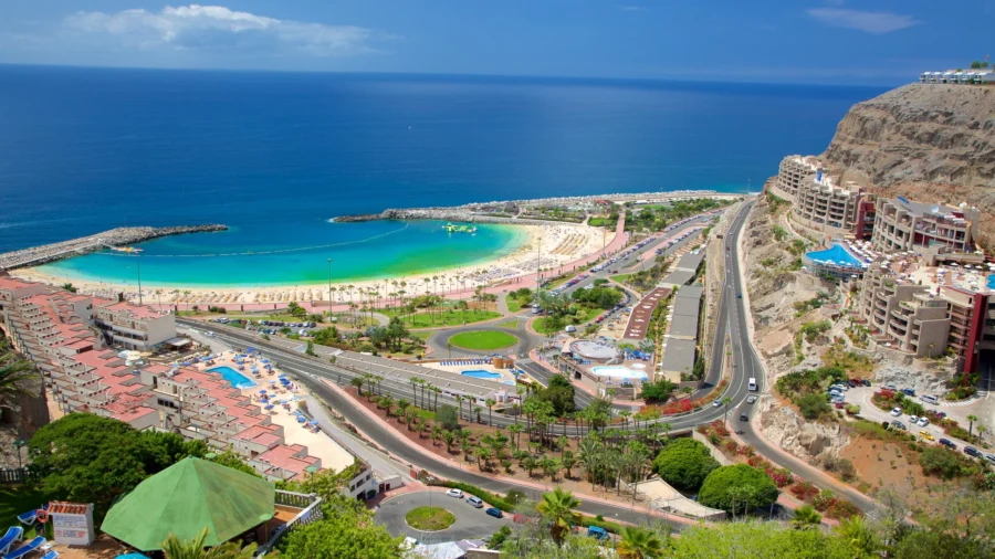 Aerial view of Puerto Rico Gran Canaria coastal resort bay, beach, hotels and turquoise sea.