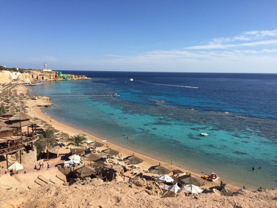 Ras Um Sid Egypt beach resort with coral reef, turquoise Red Sea water and umbrellas.