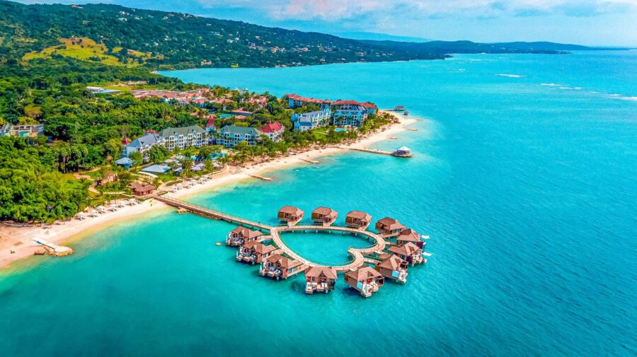 Tropical paradise with overwater bungalows and lush resort in Caribbean coastal setting.