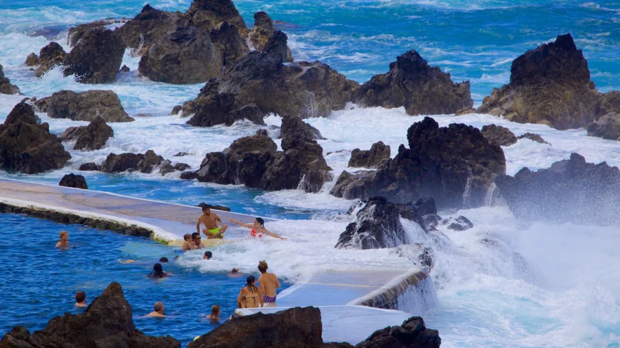 Porto Moniz, Madeira natural volcanic rock pools with swimmers and Atlantic waves.