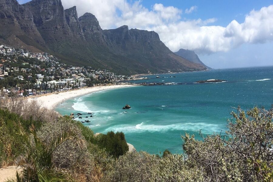 Scenic coastal beach with turquoise waters, mountains, and tropical vegetation; ideal for relaxation.