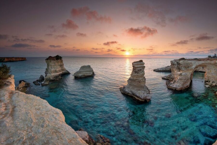 Sunset over Salento Peninsula rocks and sea, displaying stunning sky hues and tranquil waters.