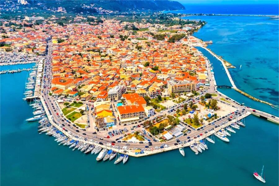 Aerial view of vibrant Lefkada marina, Mediterranean town with colorful buildings and turquoise waters.