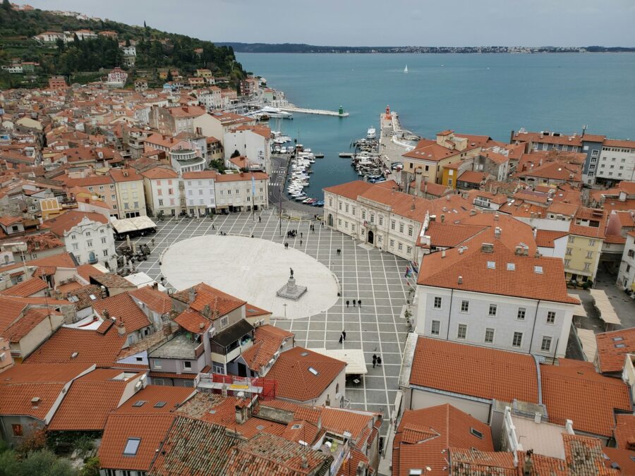 Aerial view of Piran, Slovenia: vibrant coastal town with terracotta roofs and serene sea.