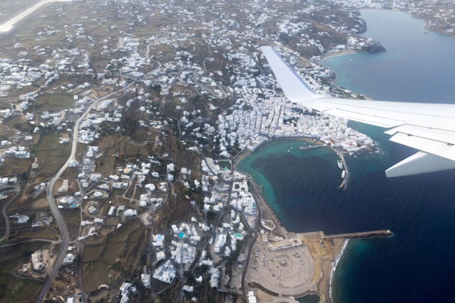 Aerial view of a Mediterranean coastal town with white buildings and serene blue bay.
