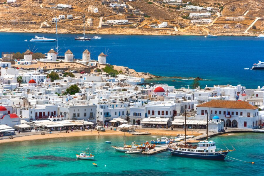 Picturesque Mykonos coastline: turquoise waters, white buildings, windmills, and vibrant island life.