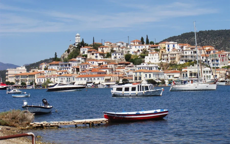 Picturesque coastal town with boats, Mediterranean architecture, and scenic hillside backdrop.