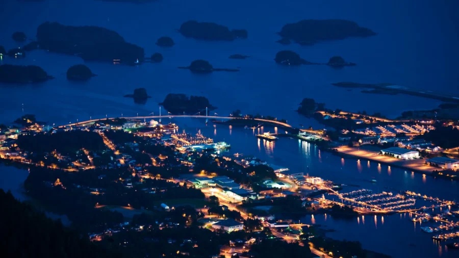 Baranof Island, Alaska coastal town at night with illuminated bridge and harbor lights.