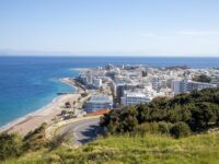 Stunning coastal town view with sandy beach, modern architecture, and clear blue waters.