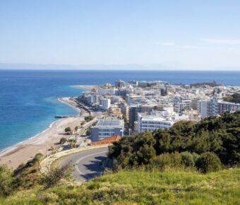 Stunning coastal town view with sandy beach, modern architecture, and clear blue waters.