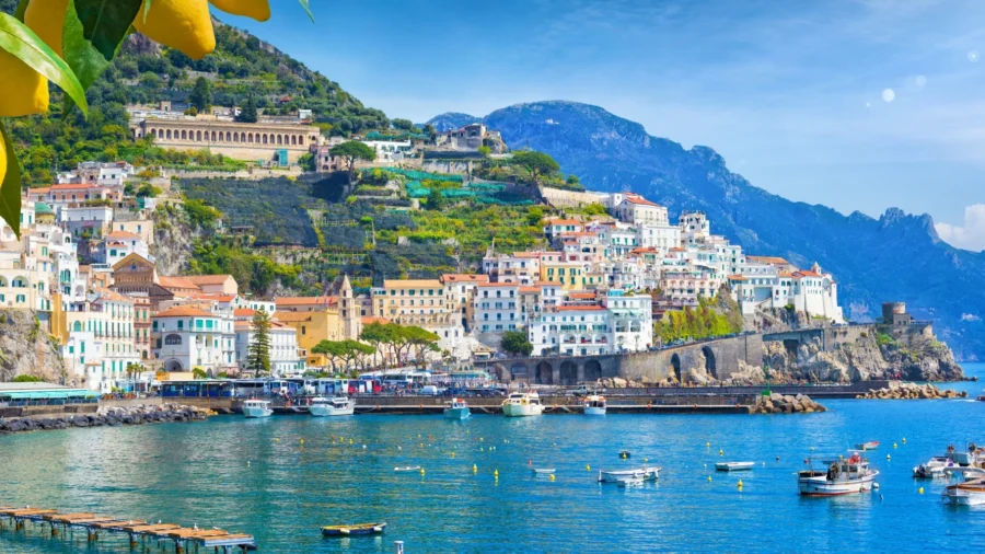 Amalfi Coast picturesque town on cliffs with colorful buildings, blue sea, boats, and lemon trees.
