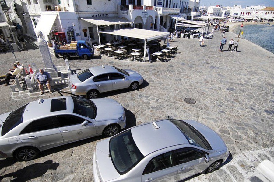 Idyllic coastal town with cars, café, promenade, and sea view.
