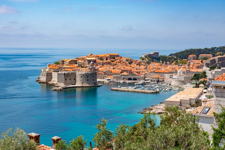 Aerial view of Dubrovnik: terracotta rooftops, Adriatic Sea, historic walls, charming harbor.