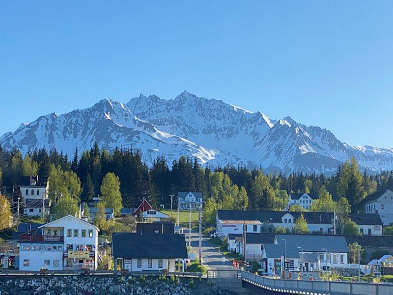 Haines, Alaska coastal town beneath snow-capped mountains and evergreen forest.
