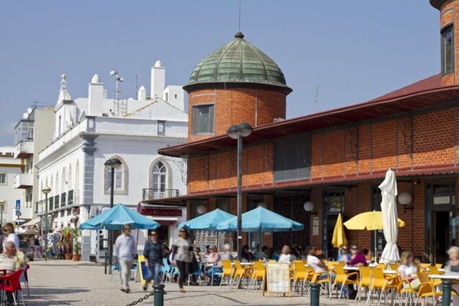 Vibrant Olhao urban plaza with colorful café, historic architecture, and lively atmosphere.