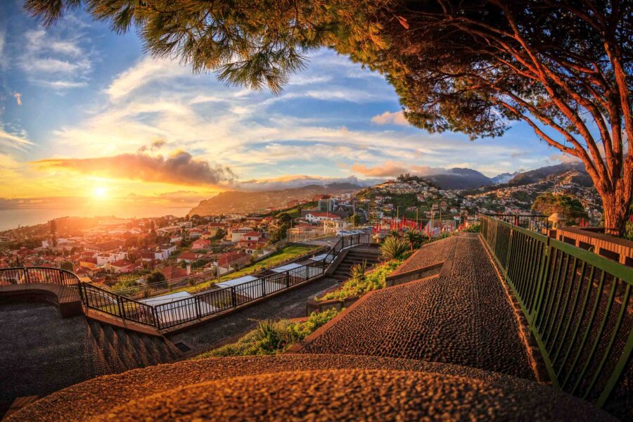Sunset over Madeira coastal city with lush greenery and scenic ocean views.