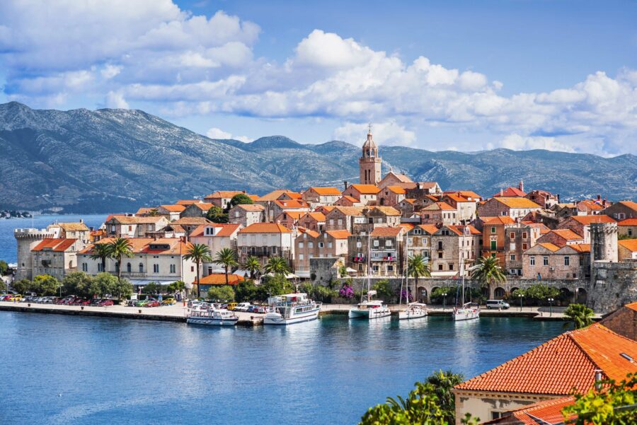 Charming coastal town with Mediterranean architecture, mountains, and waterfront promenade.
