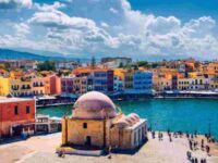 Chanias coastal scene: historic domes, colorful buildings, vibrant promenade, clear skies.