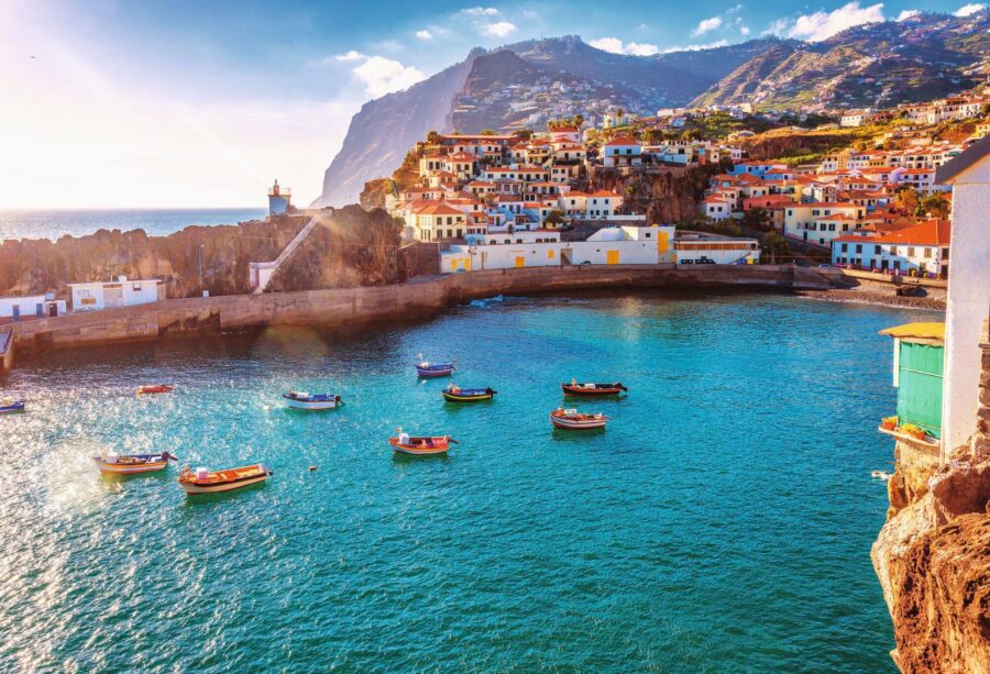 Picturesque coastal village: fishing boats, mountains, and vibrant architecture, Madeira charm.