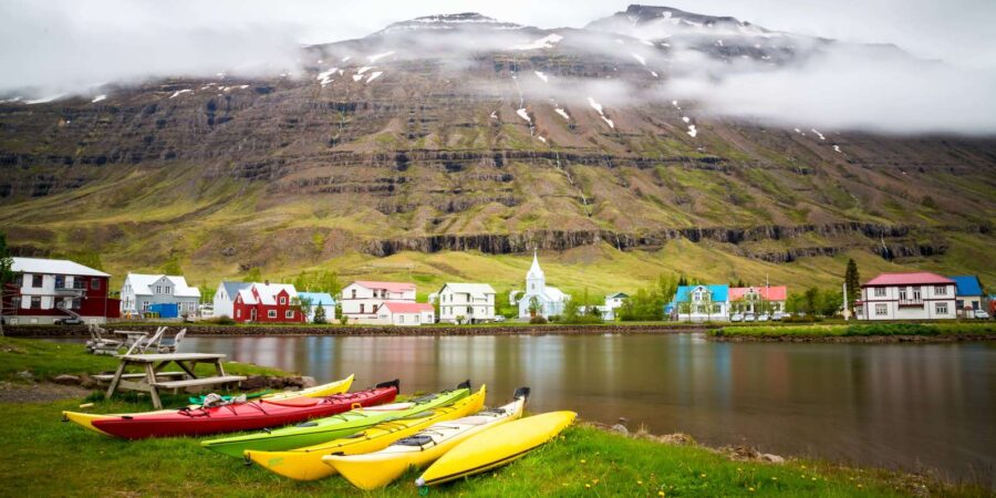 Serene mountain village with colorful kayaks by the water reflecting vibrant landscapes.