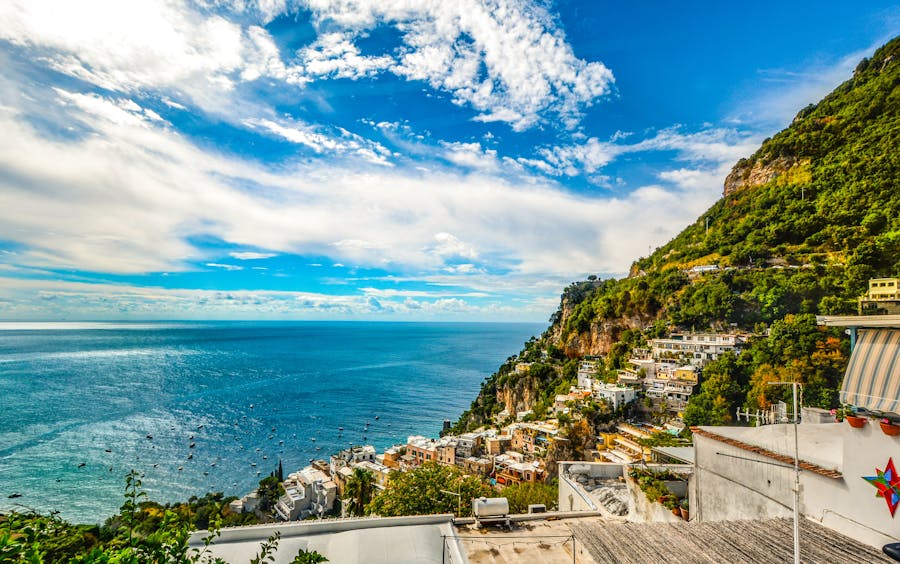 Picturesque Mediterranean seaside town with cliffs, azure sea, charming architecture, and lush greenery.