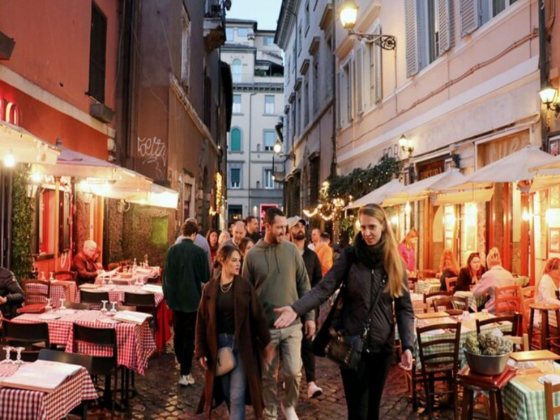 Cobblestone evening street lined with outdoor restaurants and cafés under warm lights.
