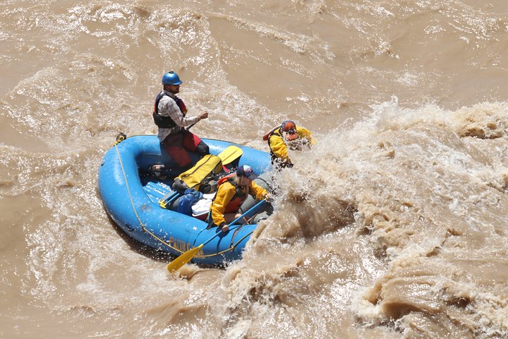 Adventurers on colorful rafts navigate the Colorado River, experiencing the thrill of whitewater rafting together.
