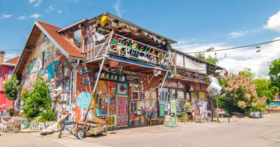 Metelkova colorful artwork-covered building with murals, graffiti, balcony, and found-object installations.