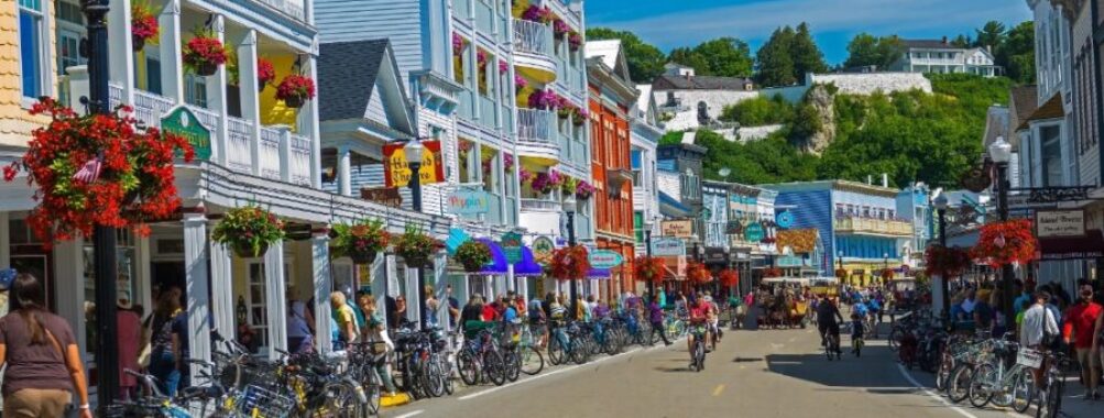 Colorful small town main street with bicycles, shops, tourists, and historic buildings on a sunny day.