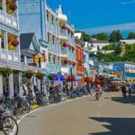 Colorful small town main street with bicycles, shops, tourists, and historic buildings on a sunny day.