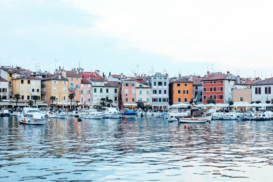 Charming coastal harbor with colorful buildings, boats, tranquil water, and inviting waterfront scene.