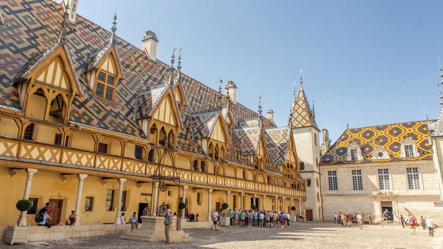 Hotel Dieu Beaune courtyard with colorful tiled roofs and medieval dormers, Burgundy, France.