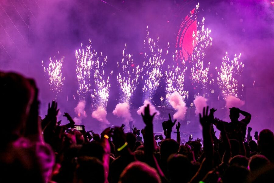 Concert crowd enjoying pyrotechnics, vibrant colors, and unity at live music festival.
