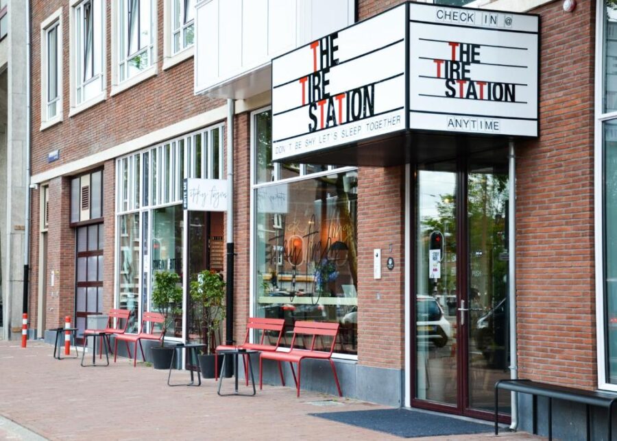Exterior of Conscious Hotel The Tire Station in Amsterdam, featuring a prominent sign that reads "the station."